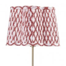 Veckad lampskärm i rött mönstrat tyg.